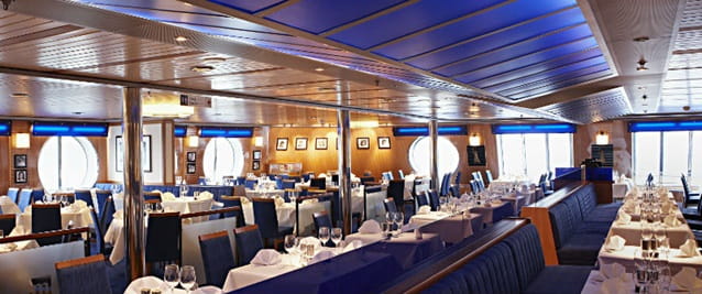 Valmiiksi katettuja pöytiä ja valkoisia pöytäliinoja laivan Metropolitan ravintolassa